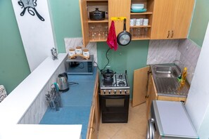 Compact kitchen with gas stove, oven, microwave, and sink, featuring ample storage and workspace.