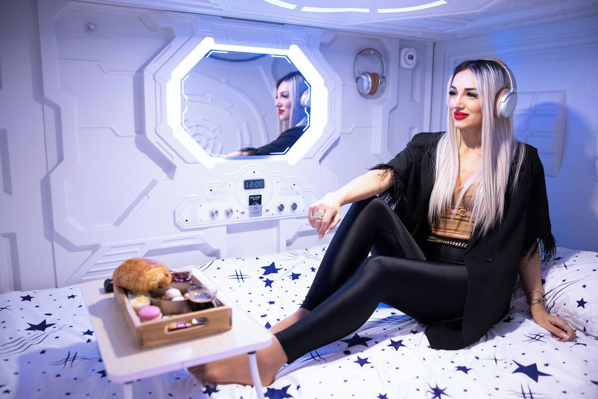 Una habitación con diseño futurista, que incluye un espejo hexagonal y una cama con cubrecama estampado con estrellas.