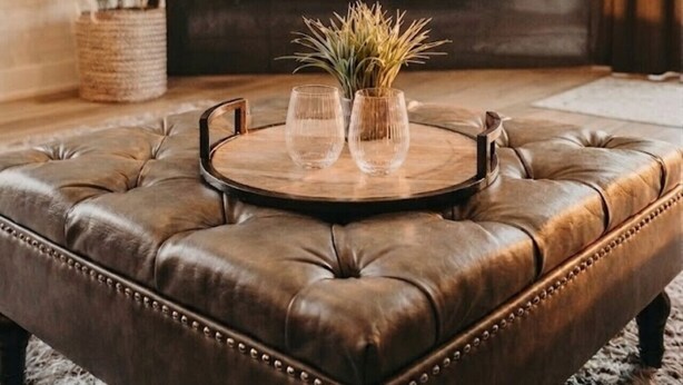 Ein Wohnzimmer mit einer Ledersofa, einem runden Couchtisch und einem flachbildfernseher, der über einem Kamin angebracht ist.