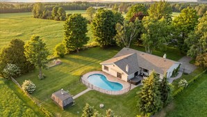 Ein Haus mit Swimmingpool, umgeben von einem gepflegten Rasen und Bäumen.
