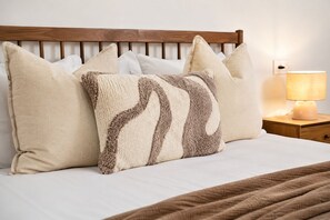 A bed with a wooden headboard, multiple pillows, a bedside lamp, and a brown blanket. - Stunning Villa | Heated Pool - Pass the Keys (Mijas)