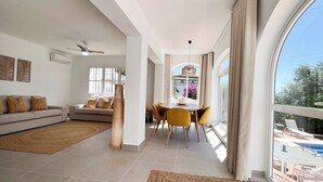 Un salon moderne avec un canapé, une table à manger, des chaises et une vue sur une piscine.