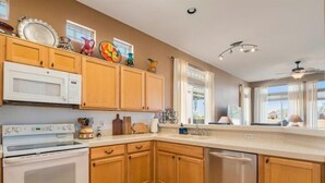 Une cuisine avec des meubles de rangement en bois, un four à micro-ondes, un four traditionnel et un lave-vaisselle.