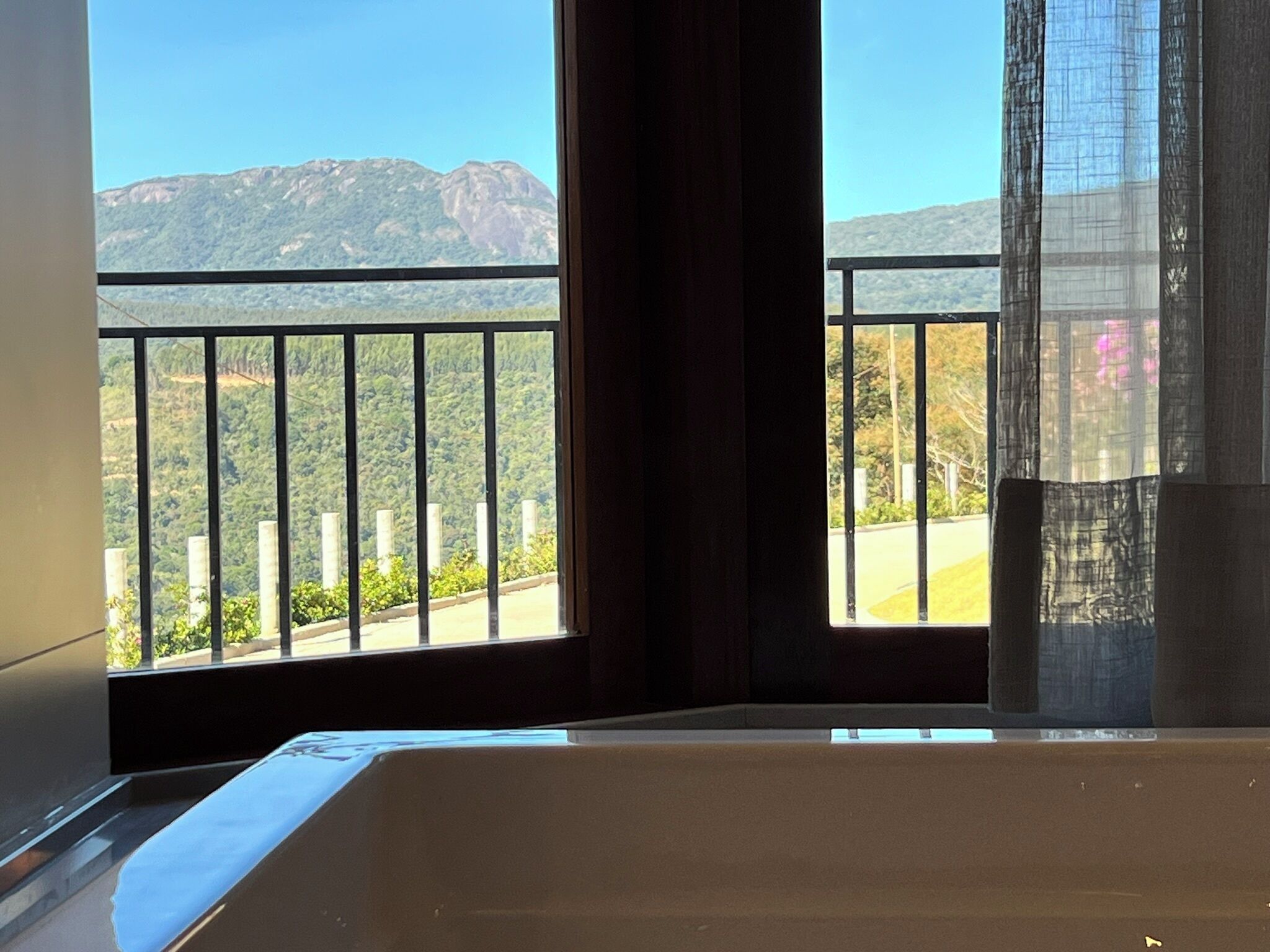 Een balkon met uitzicht op bergen en groen.