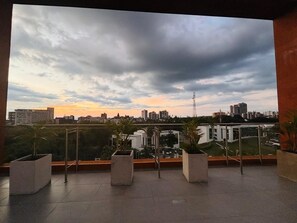 A rooftop terrace with potted plants, a metal railing, and a cityscape view during sunset. - U-GO Belmonte Armenia (Armenia)