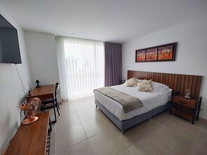 A hotel room with a bed, a desk, a chair, a TV, and a window with curtains. - U-GO Belmonte Armenia (Armenia)