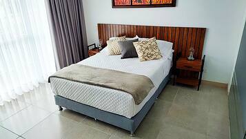 A hotel room with a large bed, a wooden headboard, a nightstand, and a painting on the wall.