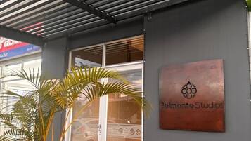 A building entrance with a metal sign reading 'Belmonte Studios' and a potted plant in the foreground.