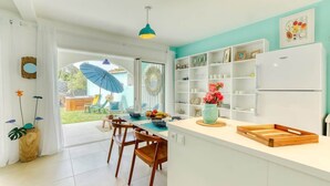 A modern kitchen with white cabinetry, a teal accent wall, and a large window.