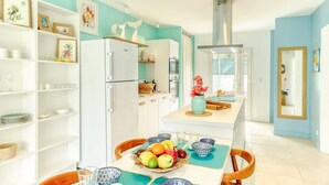A modern kitchen with white cabinets, a central island with a vase of flowers, and a fruit bowl on the island.