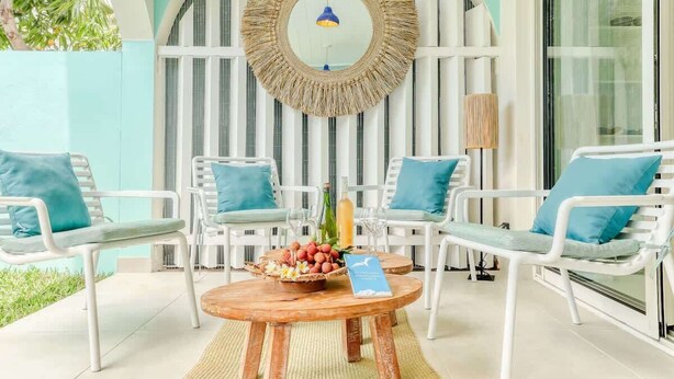 A seating area with white chairs, a round table, and a decorative mirror.