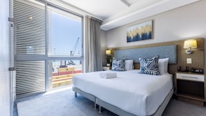 Moderni hotellihuone, jossa on suuri sänky, näköala kaupunkiin ja puinen pääty.