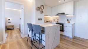 Una cucina moderna con mobili bianchi, un'isola in marmo e sgabelli da bar.
