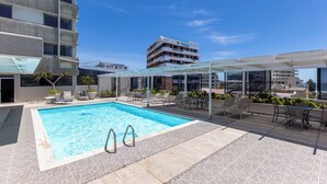Area piscina sul tetto con poltrone relax e zona salotto coperta.