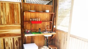 Cocina compacta con armarios de madera, un lavamanos y un taburete pequeño.