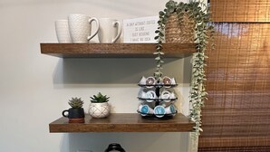 Ett kök med en kaffebryggare, muggar och en skylt med texten: ”En dag utan kaffe är som ett skämt – jag har ingen aning om hur jag skulle klara mig”.