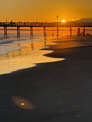 A beach scene with a pier extending into the water.