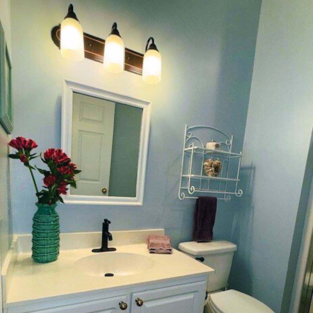 A bathroom with a white sink, a mirror, and a light fixture above it.