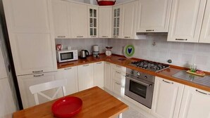 A compact kitchen with white cabinets, a wooden table, and a red bowl. - Casa Annalù With Garden Wifi Bogliasco (Bogliasco)