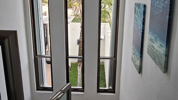 A staircase with glass railings leading to a balcony with large windows, offering views of the outdoors. - Palancar house with beautiful swimming pool and private palapa (San Miguel de Cozumel)