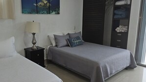 A bedroom with two beds, a nightstand with a lamp, a wall-mounted painting, and a wardrobe. - Palancar house with beautiful swimming pool and private palapa (San Miguel de Cozumel)