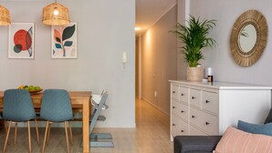 A dining area with a wooden table, two chairs, a hanging light fixture, and a wall-mounted mirror.