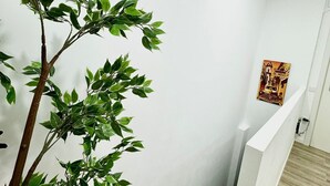 Eine Treppe mit weißer Brüstung, ein Blumentopf und eine Wand mit einem Poster.