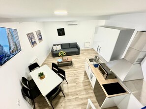 A compact living space with a dining area, kitchenette, and a sofa.