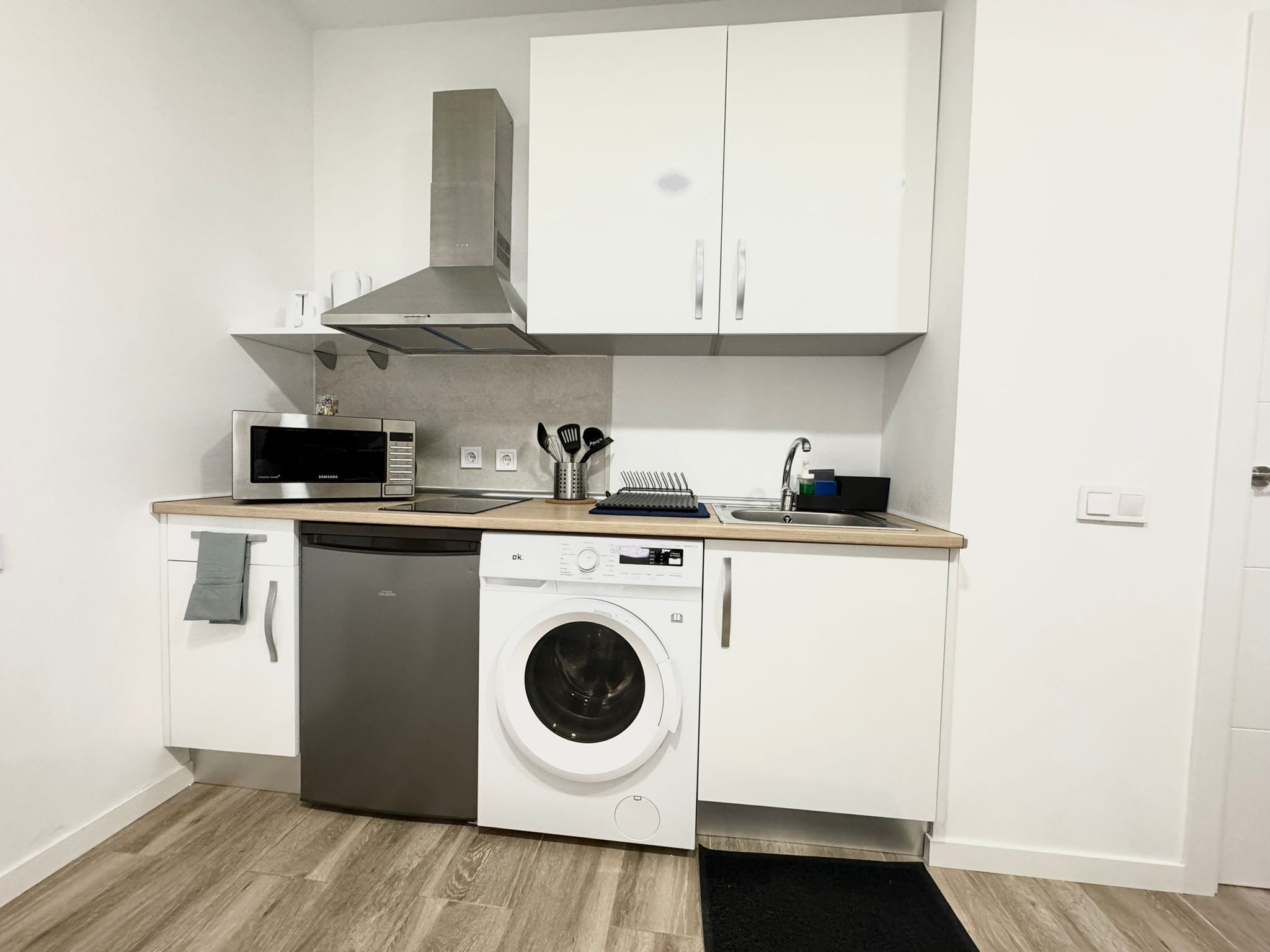 A compact kitchen with a microwave, dishwasher, and washing machine.