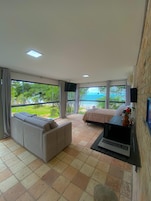 A modern room with a large window, a sofa, a bed, and a laptop on a table.