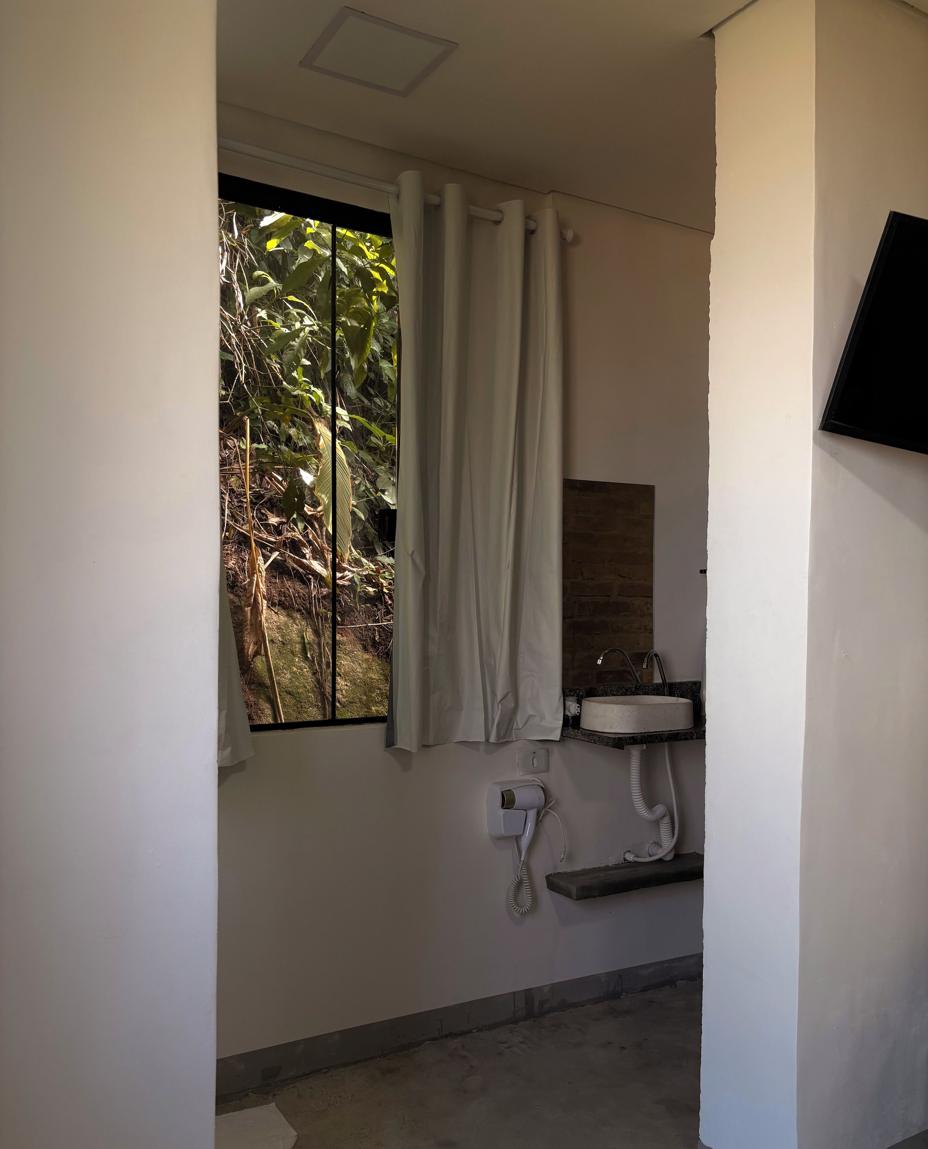 Un baño con ventana, lavamanos y secador de pelo.