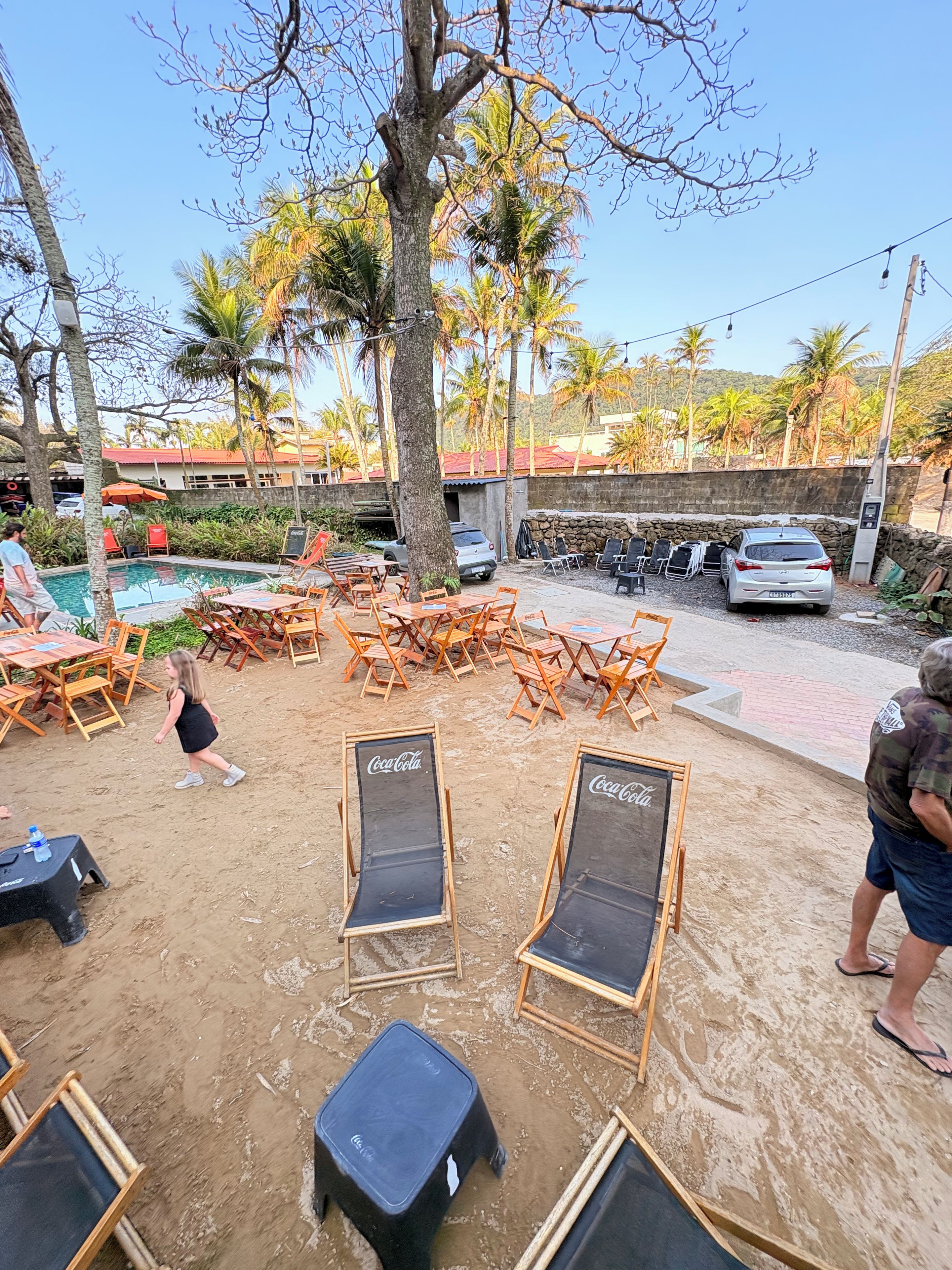 A poolside area with lounge chairs, a Coca-Cola branded cooler, and a stone wall in the background.