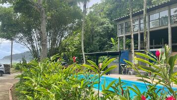 Un área de piscina con abundante vegetación y un edificio al fondo.