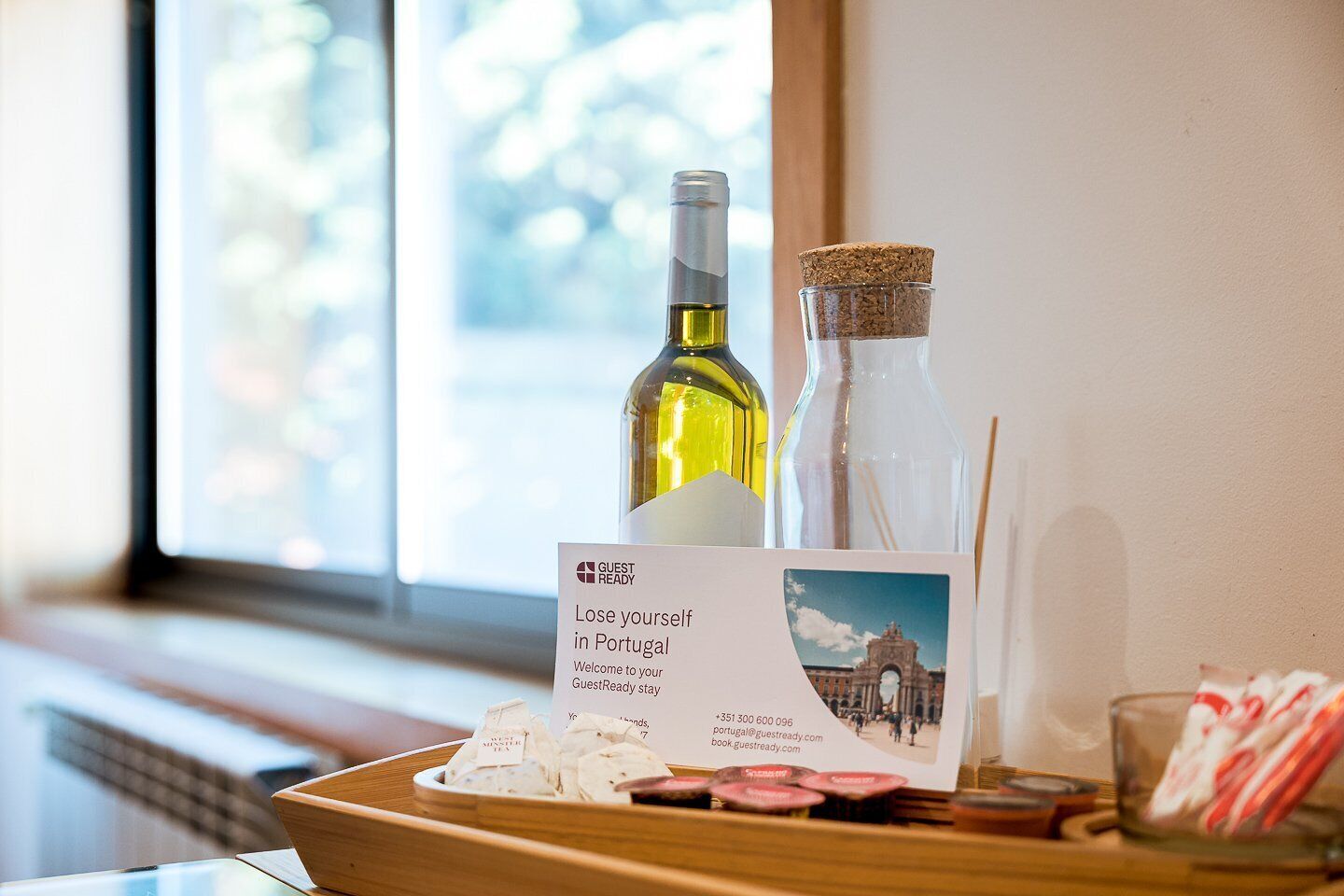 A tray with a bottle of wine, a corked glass, and a sign for GuestReady in Portugal.