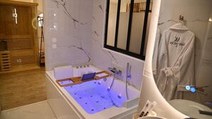 Een moderne badkamer met een groot bad, een houten sauna en een handdoekrek met een badjas.