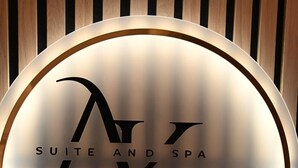 Een rond bord met de tekst 'M & K SUITE AND SPA' tegen een houten achtergrond.