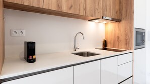 Cocina moderna con gabinetes de madera, un lavamanos de acero inoxidable y un microondas empotrado.
