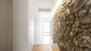 A hallway with a stone wall on the right and a door at the end. - Feel Porto Lapa Collection Flat 1 2 (Porto)