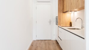 A compact kitchen with white cabinets, a wooden countertop, and a built-in microwave. - Feel Porto Lapa Collection Flat 1 2 (Porto)