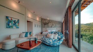 A modern living room with a sofa, a bean bag, a coffee table, and a painting on the wall.