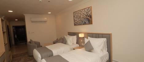 Habitación de hotel con dos camas, un sofá, un cuadro y un equipo de aire acondicionado.