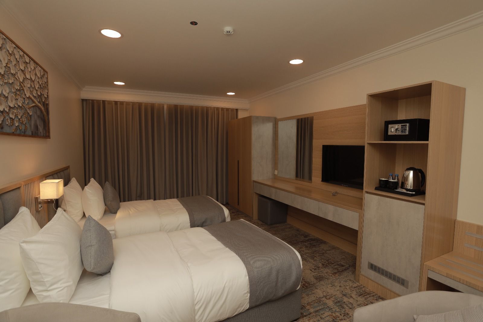 A hotel room with two beds, a TV, a desk, and a minibar.