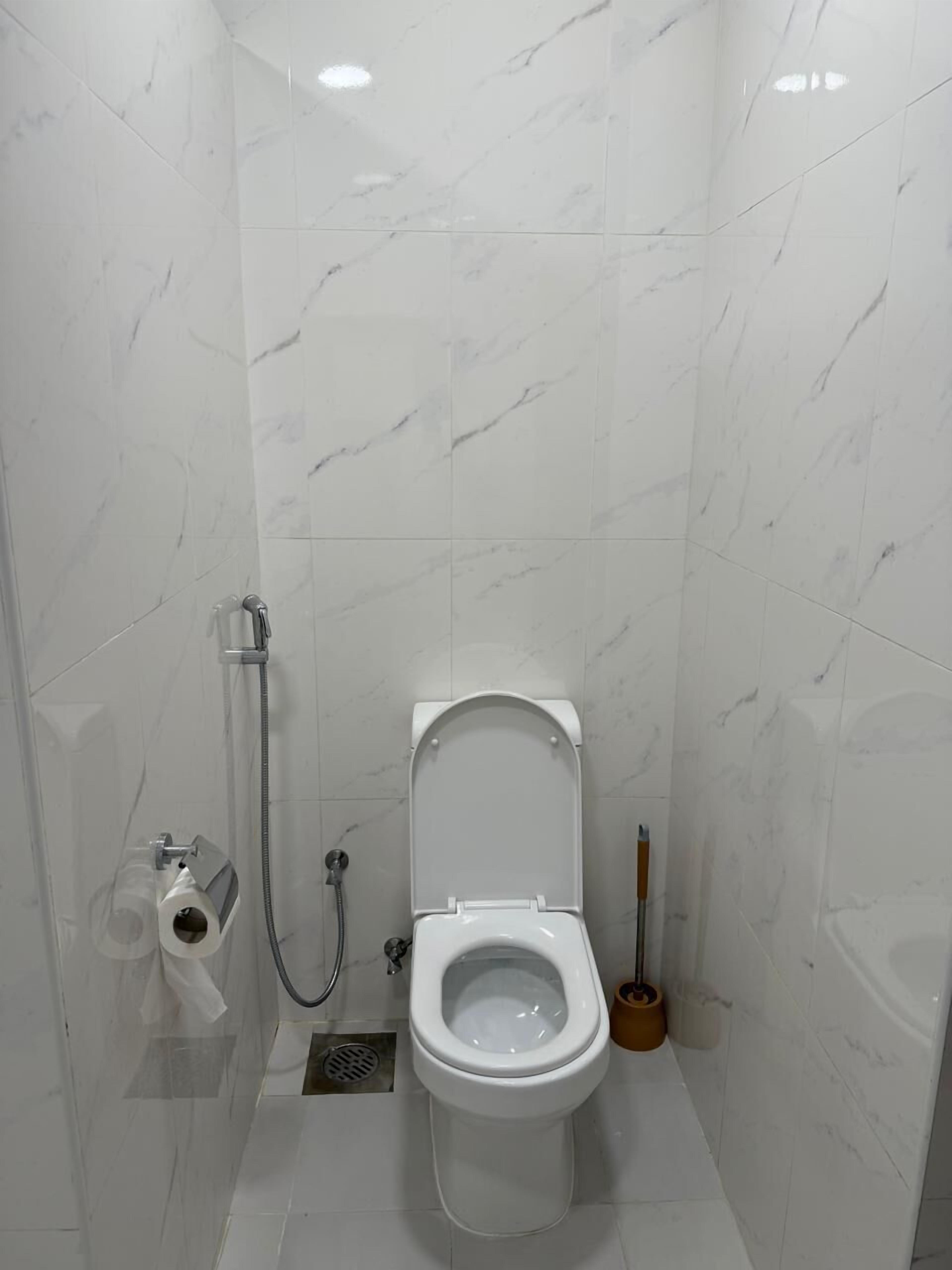 A small, modern bathroom with a toilet, a shower, and a toilet paper holder.