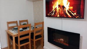 A dining area with a TV mounted above a fireplace.
