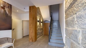 A modern interior with a stone wall, a wooden column, a staircase, and a large abstract painting. - Urbanfive 4A Ourense downtown 3 rooms (Ourense)