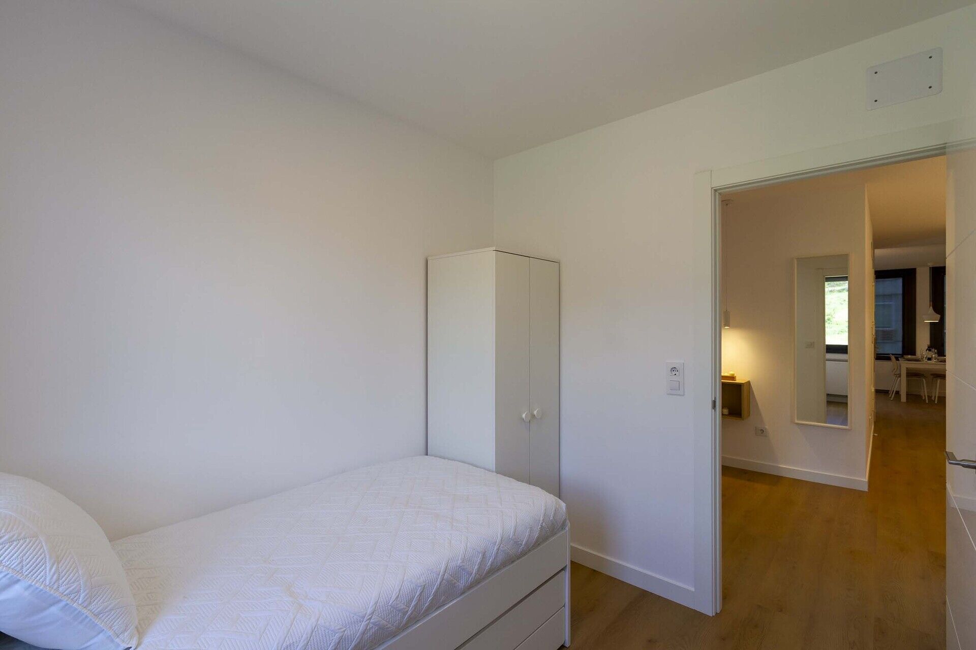 Un dormitorio con una cama individual, un armario y una puerta que da a un baño.