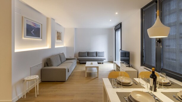 A modern living room with a sofa, a dining table set for two, and a small coffee table. - Urbanfive 4A Ourense downtown 3 rooms (Ourense)