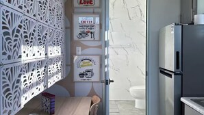 A modern kitchen with a marble backsplash, a refrigerator, and a dining area with a table and chairs.