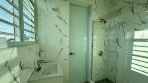 A bathroom with a white sink, a door, and a glass shower enclosure.