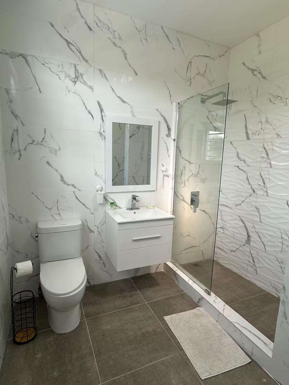 Un baño con inodoro, lavabo, espejo y ducha.